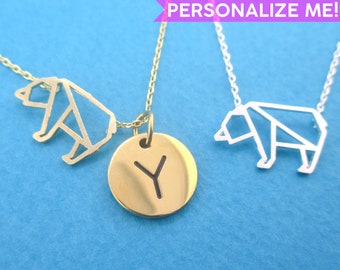 May include: Gold and silver-toned necklaces with bear pendant designs. One necklace features a gold disc pendant with the letter "Y". The background is a solid light blue. Text in the image reads "PERSONALIZE ME!"