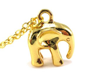May include: A gold-colored elephant pendant necklace. The pendant is a detailed, three-dimensional elephant with a raised trunk and small tusks. The necklace chain is also gold-colored and delicate. The elephant charm is approximately 0.75 inches in height.