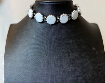 May include: A white choker necklace with round, white, rhinestone-encrusted stones.