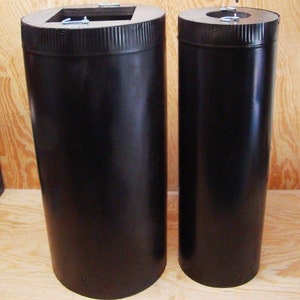 May include: Two black metal chimney pipes with a diameter of approximately 6 inches and 8 inches. The pipes are made of metal and have a black finish. The pipes are sitting on a wooden surface.