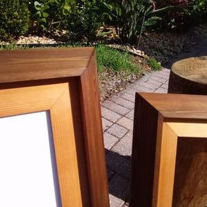 Pu&ograve; includere: Due cornici per foto in legno con finitura in legno naturale. La cornice pi&ugrave; grande &egrave; realizzata in due tipi di legno, con una cornice esterna in legno pi&ugrave; scuro e una cornice interna in legno pi&ugrave; chiaro. La cornice pi&ugrave; piccola &egrave; realizzata in un solo tipo di legno con finitura in legno pi&ugrave; scuro.
