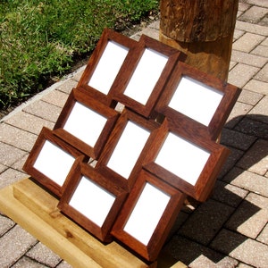 May include: A set of eight wooden picture frames arranged in a pyramid shape. The frames are all the same size and have a dark brown finish. The frames are empty and ready to be filled with photos.
