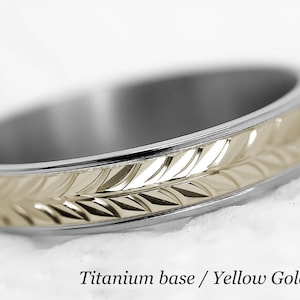May include: A titanium wedding band with a yellow gold centre band. The centre band has a leaf pattern.