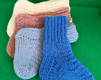 May include: Three pairs of knitted socks in different colors: light blue, brown, and cream. The socks are folded and stacked on top of each other.