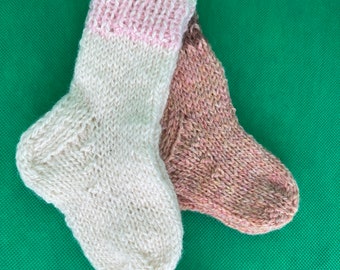 May include: Two pairs of knitted socks, one white with a pink cuff and one brown with flecks of pink and white.