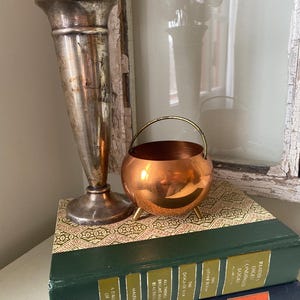 May include: A white ceramic mug with a black handle and the text "But First, Coffee" in a black, handwritten-style font. The mug is on a white surface.