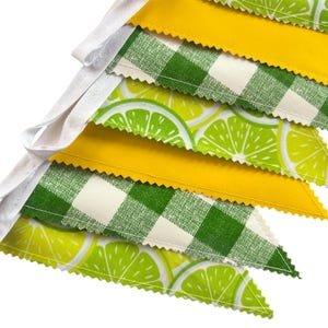 May include: A lime green and yellow fabric banner with a checkered pattern and lime slices. The banner is strung together with white ribbon.