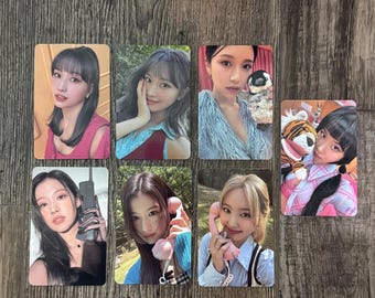May include: Seven rectangular photo cards featuring women. Each card shows a portrait of a woman, some holding phones or toys. The cards are arranged on a wooden surface, with a natural wood grain.
