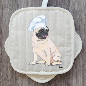 May include: Off-white, square pot holder with a pug wearing a chef's hat. The pug is light tan with a black muzzle and is sitting. The pot holder has a loop for hanging and a scalloped edge.
