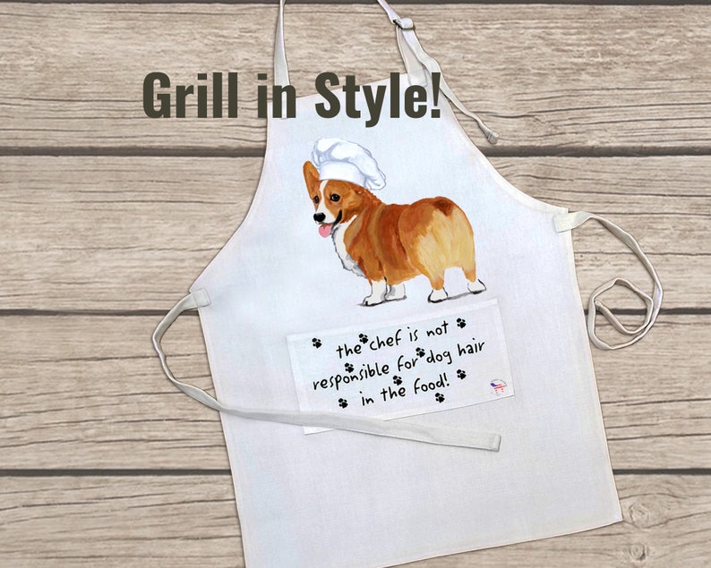 May include: White cotton apron with a pocket featuring a cartoon image of a corgi wearing a chef's hat. The text on the pocket reads "the chef is not responsible for dog hair in the food!"