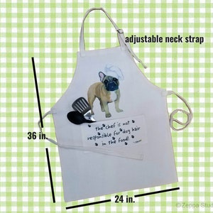 May include: White cotton apron with an adjustable neck strap. It features a cartoon image of a French Bulldog wearing a chef's hat and the text "the chef is not responsible for dog hair in the food!"