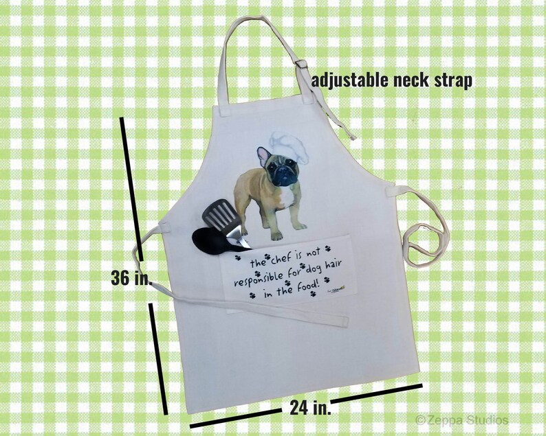 May include: White cotton apron with an adjustable neck strap. It features a cartoon image of a French Bulldog wearing a chef's hat and the text "the chef is not responsible for dog hair in the food!"