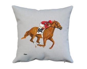 May include: A gray throw pillow with a painting of a brown horse and a jockey wearing a red and white uniform. The horse is running and the jockey is leaning forward. The number "6" is visible on the jockey's uniform and the horse's saddle.