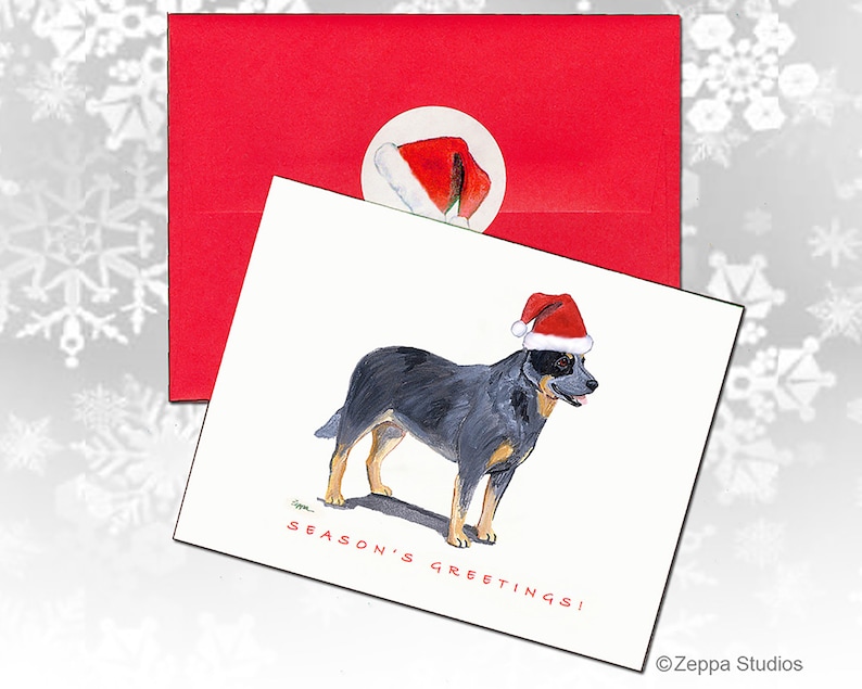 May include: A Christmas card featuring a blue heeler dog wearing a Santa hat. The card has the text "Season's Greetings!" and is signed "Zepppa Studios".