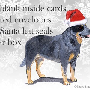 May include: A blue heeler dog wearing a red Santa hat, standing on a white snowflake background. The text on the image reads: "8 blank inside cards, 8 red envelopes, 8 Santa hat seals per box".