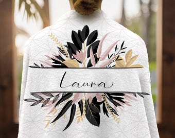 May include: White personalized spa robe with a floral design in black, blush pink, and gold. The name "Laura" is displayed in elegant script across the center. The robe is made of a soft, textured fabric.