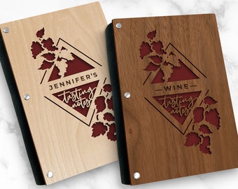 May include: Two wooden wine tasting notebooks. One is light-colored with "Jennifer's Tasting Notes" and the other is dark-colored with "Wine Tasting Notes". Both have a laser-cut grape design and a red background.