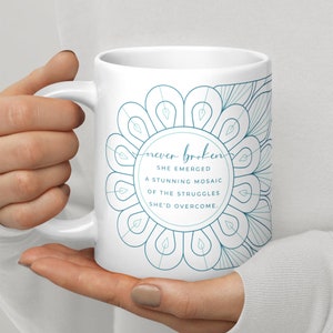 May include: White ceramic mug with a blue mandala design and the text "never broken she emerged a stunning mosaic of the struggles she'd overcome."