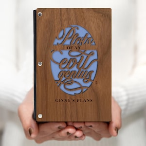 May include: A wooden photo album with a blue cutout design that says "Photos of an evil genius" and "Ginny's Plans".