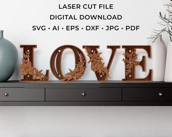 May include: Wooden "LOVE" sign with floral accents. The letters are brown and stand on a black shelf. The sign is a laser cut file digital download available in SVG, AI, EPS, DXF, JPG, and PDF formats.