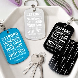 May include: Keychains in blue, silver, and black, each with a dog tag shape and a silver keyring. The tags feature the text "BE STRONG & COURAGEOUS. THE LORD YOUR GOD WILL BE WITH YOU WHEREVER YOU GO. JOSHUA 1:9."