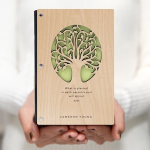 May include: A wooden journal featuring a tree of life design and the quote "What is planted in each person's soul will sprout." by Rumi. The journal is personalised with the name CAMERON YOUNG.
