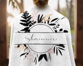 May include: White personalized blanket with a floral design. The blanket features a circular emblem with the name "Shannon" in cursive script. The design includes black, gold, and pink botanical elements.