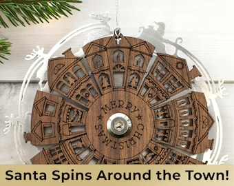 May include: A wooden Christmas ornament with a spinning wheel featuring a town with houses and the words "Merry Christmas". Santa is depicted in the silver metal frame around the wheel.