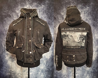 Military-style Jacket in Black cotton with Zippers, visible white Hand-stitched seams, and 8 pockets