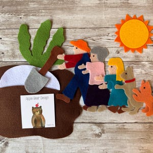 Peut inclure: Ensemble de personnages en feutre représentant une famille d'ours, un chien et un chat. L'ensemble comprend un arbre en feutre brun, une lune en feutre blanc et un soleil en feutre jaune. L'ensemble comprend également une carte avec le texte "Apple Bear Design" et un message de remerciement.