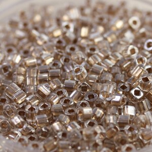 May include: A close-up view of a large quantity of small, clear glass beads with a gold iridescent sheen.