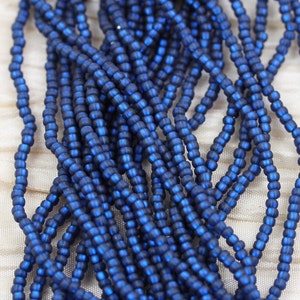 May include: A strand of dark blue glass seed beads. The beads are small and round, and they have a matte finish.