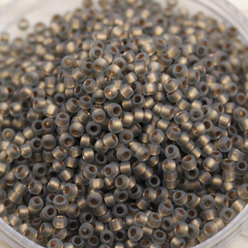 May include: A close-up view of a pile of small, round, gray glass beads with a metallic sheen.