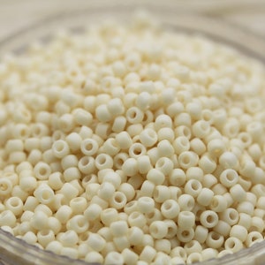 May include: A close-up image of a bowl filled with small, white, round beads. The beads are arranged in a random pattern and appear to be made of a smooth, opaque material.