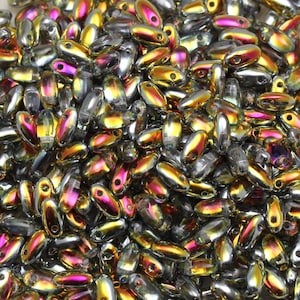 Könnte beinhalten: Eine große Menge an irisierenden Glasperlen in einer Mischung aus Gold-, Silber- und Rosatönen. Die Perlen sind oval geformt und haben eine glatte, glänzende Oberfläche.