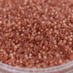 May include: A close-up of a large quantity of small, round, translucent, light brown seed beads.