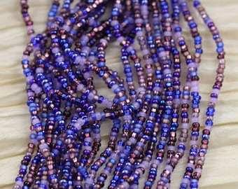 May include: A strand of seed beads in shades of purple, blue, and lavender. The beads are small and uniform in size, creating a smooth and elegant look.