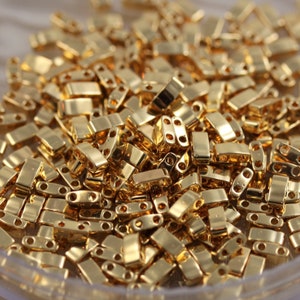 Puede incluir: Un montón grande de cuentas de metal de color dorado. Las cuentas son de forma rectangular y tienen dos pequeños agujeros en cada extremo.