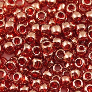 Puede incluir: Una imagen de primer plano de un montón de pequeñas cuentas redondas y metálicas. Las cuentas son de color cobre brillante.