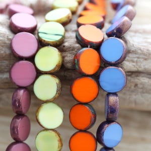 May include: Five strands of round, flat beads in various colors. The beads are arranged in a row, with the colors alternating. The colors are purple, yellow, orange, blue, and purple.