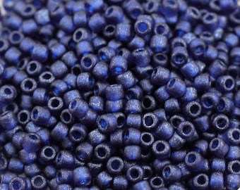May include: A close-up view of a large quantity of small, round, dark blue glass beads. The beads have a matte finish and a slightly iridescent sheen.