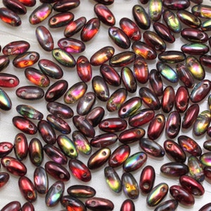 Peut inclure: Un grand assortiment de perles de verre irisées de couleur bordeaux foncé. Les perles sont de forme ovale et ont un trou en haut pour être enfilées.