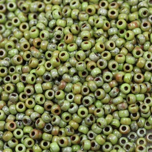 May include: A close-up view of a large quantity of small, round, green glass beads. The beads have a mottled, marbled appearance with a slight sheen.