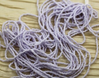 May include: A close-up of a large spool of light purple seed beads. The beads are small and round, and they are arranged in a loose, tangled pile.