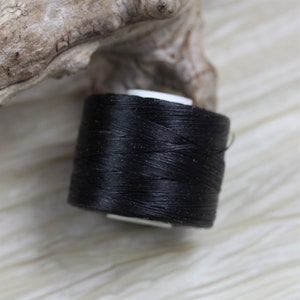 May include: A spool of black thread for sewing or crafting.