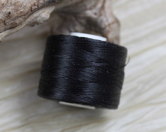 May include: A spool of black thread for sewing or crafting.