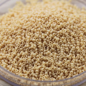 以下が含まれることがあります： クリーム色の小さなパスタリングでいっぱいのボウルをクローズアップ。パスタはランダムなパターンで配置されており、テクスチャのある表面になっています。