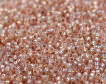 May include: A close-up view of a large quantity of small, round, iridescent pink beads with a metallic gold finish.