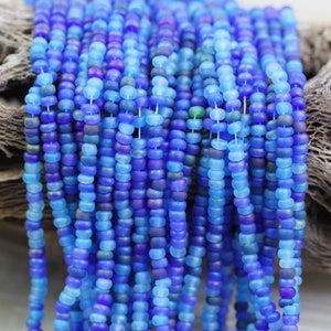 May include: A strand of blue and purple glass beads. The beads are small and round, and they have a frosted finish.