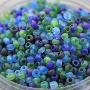 May include: A close-up of a collection of small, round, frosted glass beads in shades of blue, green, and purple.